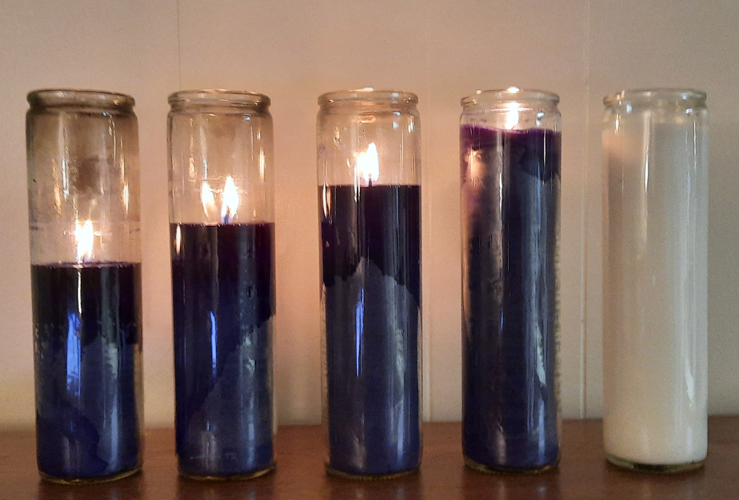 Four lit purple candles and an unlit white candle.