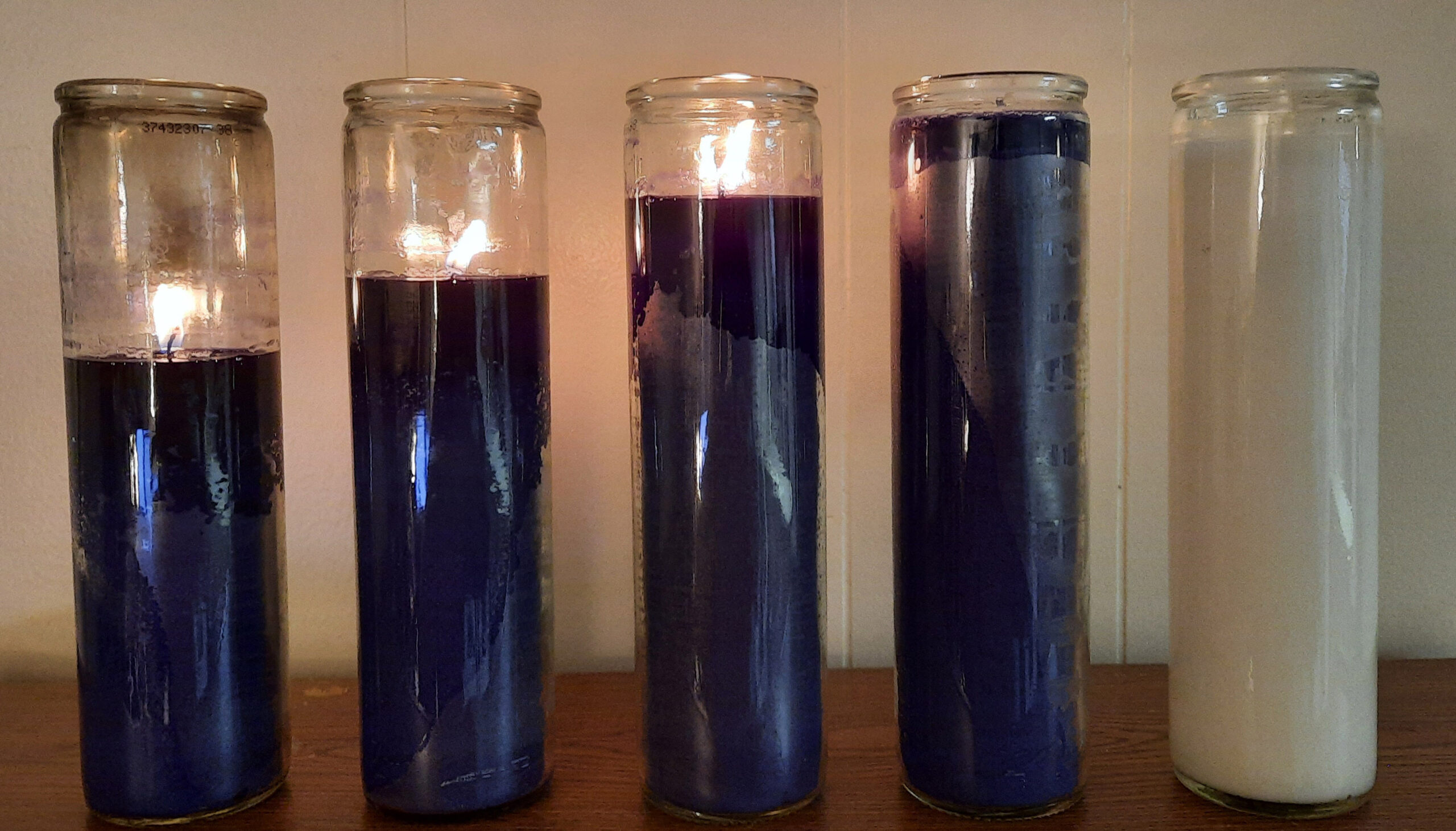 Four purple candles and a white candle, with three of the candles lit.