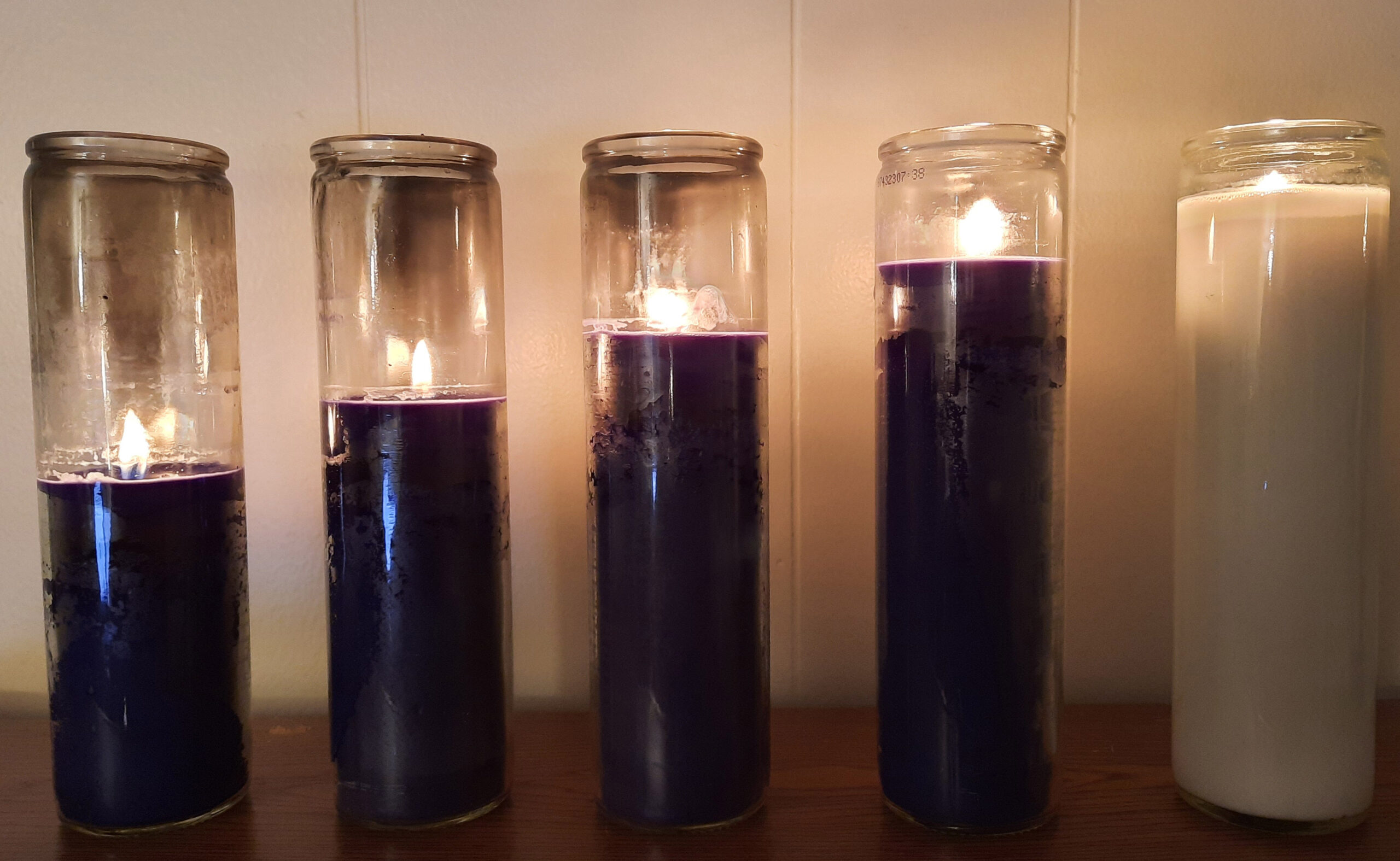 Five lit Advent candles: Four purple and one white.